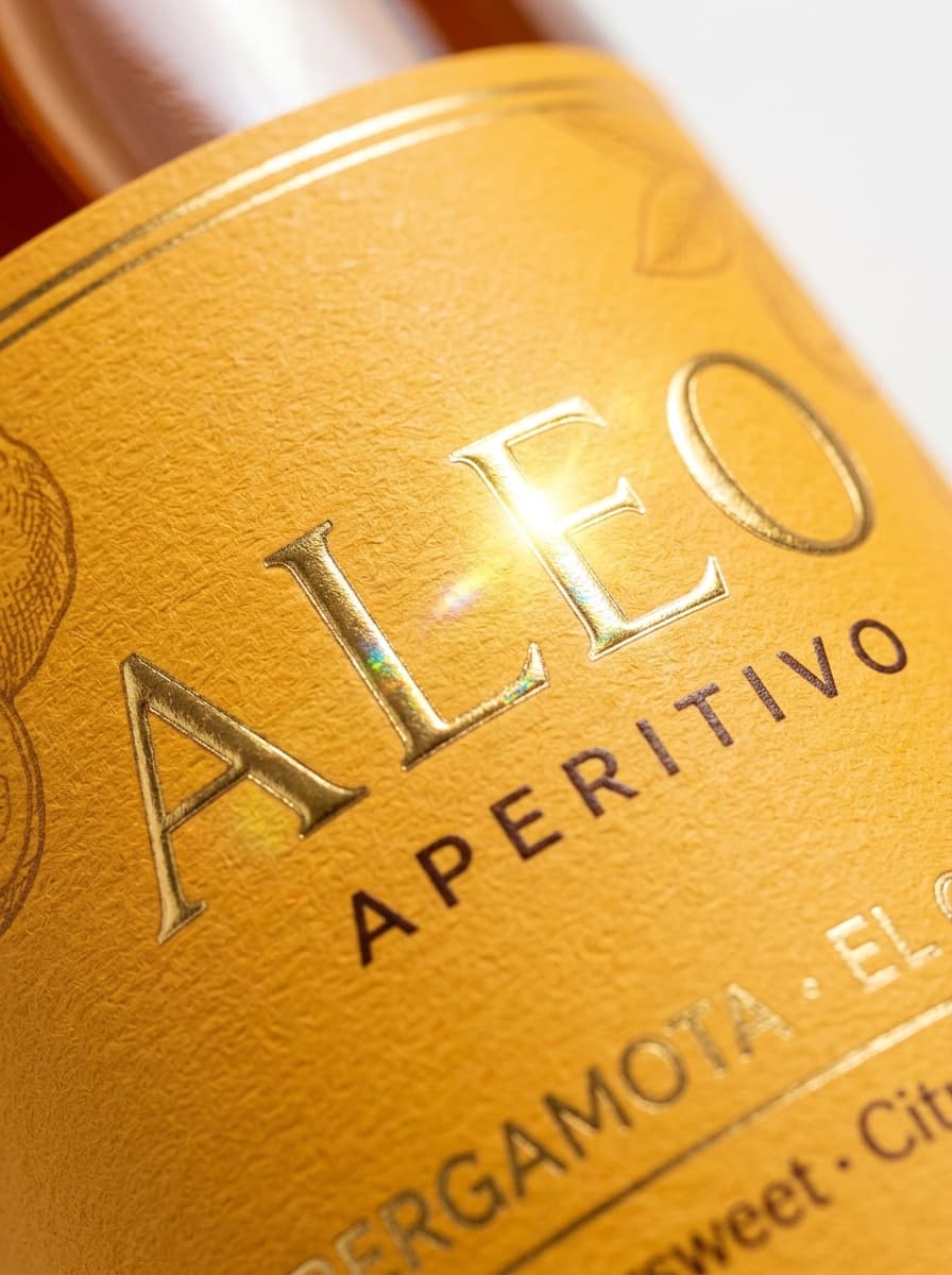Close-up of the Aléo aperitivo gold foil label with bergamot and citrus notes
